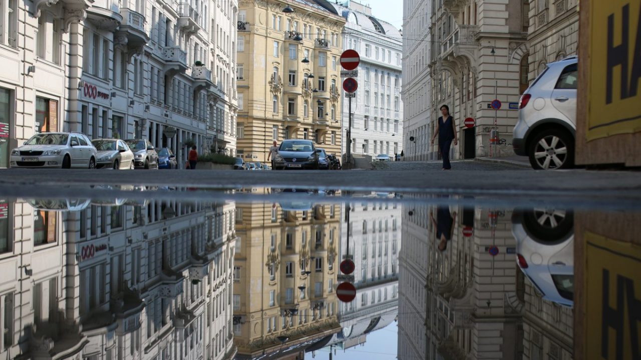 Spiegelung von Gebäuden einer Straße in Budapest in einer großen Pfütze.